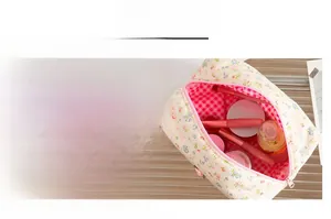Dettaglio della trousse in velluto floreale con cerniera rosa e fodera a quadri rossi