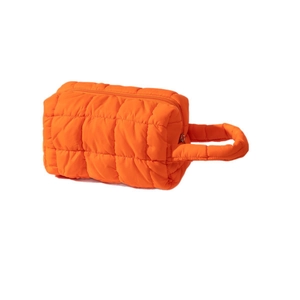 Quilted bright orange cosmetic bag with a padded handle and top zipper closure
