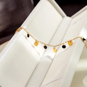 Detailed macro view of gold heart and black disc charms on a luxury bracelet in a gift box