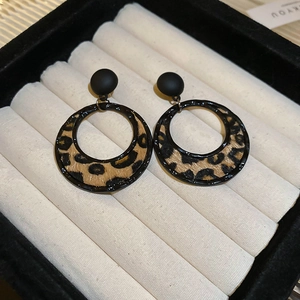 Detail view of round leopard print earrings with black studs in a velvet gift box