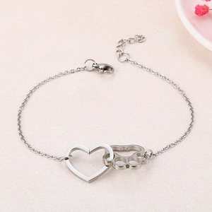 Macro view of silver paw print and heart charms on a sleek stainless steel necklace
