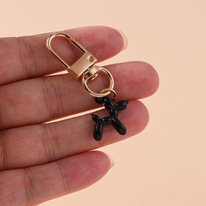 Detail of glossy black balloon dog keychain with gold metal clasp held in hand