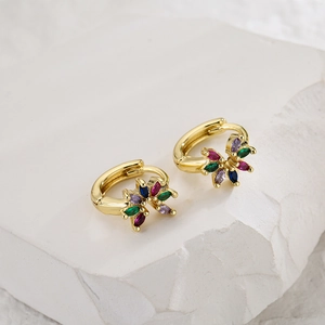 Gold hoop earrings featuring colorful zircons in floral design on stone background