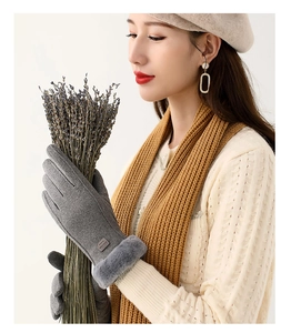 Detail of gray winter gloves featuring plush faux fur cuffs and a fashion label decoration