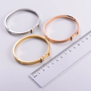 Detail view of gold and silver bangles with crystal inlay next to a measuring scale