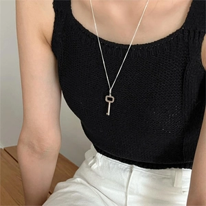 Minimalist 925 sterling silver key pendant necklace worn by model on a simple background