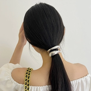 Close-up of a silver double-layered metal hair tie securing a ponytail on a model