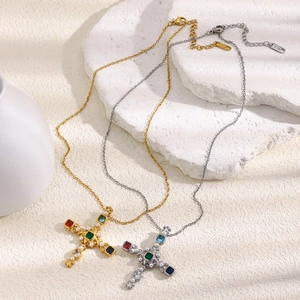 Detail of gold and silver cross necklaces with colorful gems and pearls on white stone
