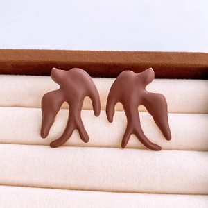 Detailed macro view of dark brown matte swallow bird stud earrings on velvet display