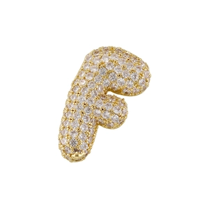 Detailed macro view of gold-plated cubic zirconia letter F pendant with pave stones