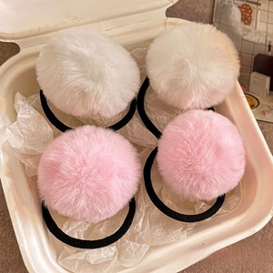 Detail of soft plush faux fur pom pom hair ties in white and pink, four-piece set
