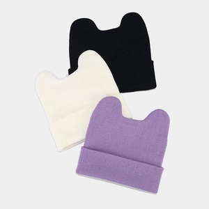 Flat lay of cat ear knit hats in black, beige, and purple showing texture