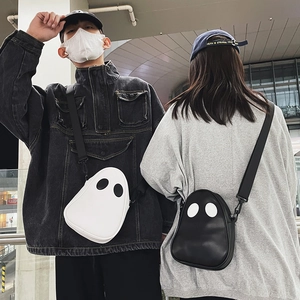 Close-up of black and white cartoon ghost crossbody bags in a street style setting