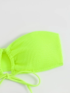 Detailed macro of fluorescent green smocked fabric and side ties on a bandeau bikini