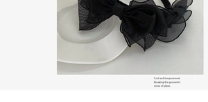 Close-up of a French vintage black mesh layered bow headband on a white ceramic plate