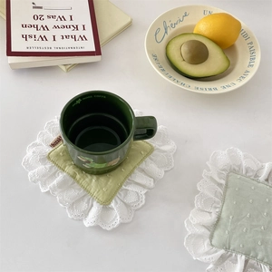 Close-up of a mint green quilted coaster with white lace edges and polka dot texture