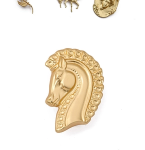 Macro detail of vintage matte gold horse head brooch with baroque style metal engraving