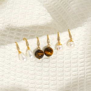 Three pairs of elegant gold-plated drop earrings featuring pearls and tiger eye stones
