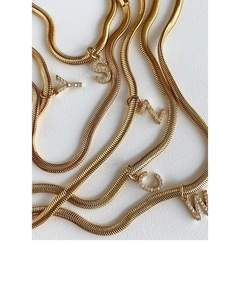 Macro view of gold snake bone necklaces with crystal-encrusted letter S N C W pendants