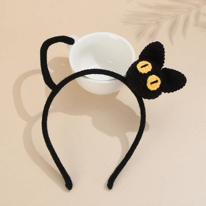 Detail of a handmade black knitted cat headband with yellow embroidered eyes