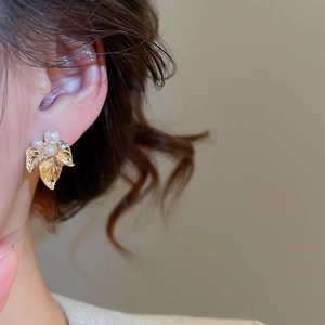 Gros plan sur boucles d'oreilles feuille dorée avec perles blanches et cristaux