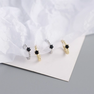 Detail showing gold and silver beaded hoop earrings with black zircon stone in six-prong setting