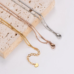 Three-color bead snake chain bracelets in gold, silver, and rose gold on beige stone