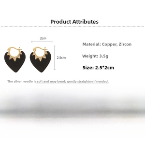 Détail macro de boucles d'oreilles cœur noir avec bordure dorée et zircons