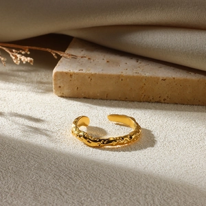 Detailed view of golden irregular textured ring with organic wave pattern on beige cloth