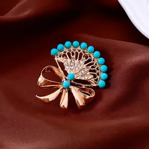 Vintage gold fan-shaped bow brooch with sky blue beads and crystals on silk background