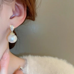 Macro shot of a high-quality white pearl earring with sparkling zircon on a female model