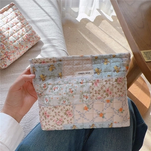 Dettaglio della borsa da trucco in cotone trapuntato a fiori con etichetta semplice