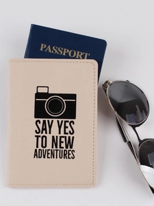 Beige PU leather passport cover with camera print and travel quote on white background