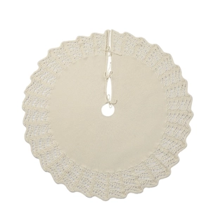 Close-up of cream knitted Christmas tree skirt with scallop wavy edge and bow ties
