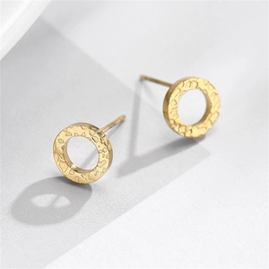 Macro view of gold minimalist earrings with a textured hammered finish on circular studs