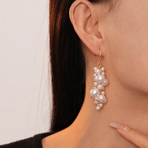 Close-up of vintage baroque faux pearl tassel earrings worn by a model in profile