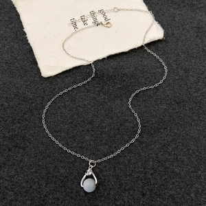 Detailed close-up of a silver necklace featuring a blue gemstone pendant on a felt background