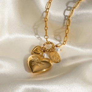 Gold stainless steel heart locket necklace with pearls on a white silk background