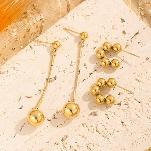 Minimalist gold ball drop earrings and stud set displayed on a natural stone background