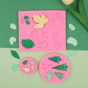 Nahaufnahme von rosa Silikonformblättern und fertigen grünen Ahornblättern aus Fondant
