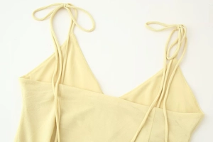 Detail of light yellow midi dress featuring adjustable double shoulder tie-up ribbons