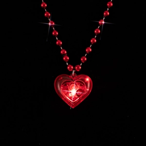 A close-up shot of a red LED glowing heart necklace with beads on a black background