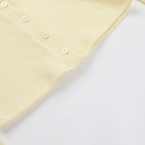 Dettaglio ravvicinato del cardigan in maglia crema con trama a coste e bottoni tondi