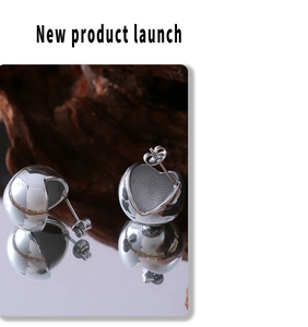 Macro view of silver hollow ball earrings with frosted interior on wooden surface