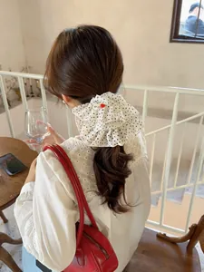 Close-up of white polka dot scrunchie with ruffle edges and handmade heart label