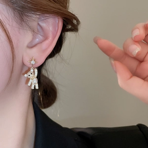 Close-up of sparkling teddy bear drop earrings with rhinestone star stud on model