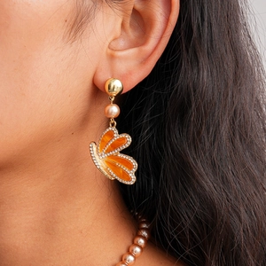 Vue détaillée des boucles d'oreilles papillon avec ailes orange et détails en perles