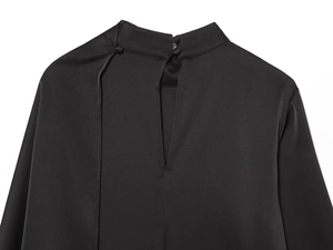 Détail d'un haut en satin noir avec col montant, boutons en tissu et découpe dans le dos