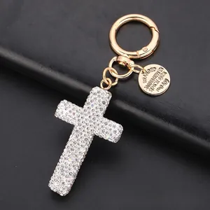 Close-up of sparkling full rhinestone cross keychain with gold spring buckle on leather