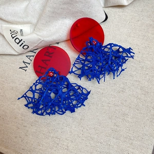 Détail de boucles d'oreilles artistiques en maille rouge et bleue avec acrylique